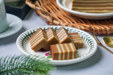 A traditional Indonesian steamed layer cake with alternating vibrant layers, showcasing a soft,...