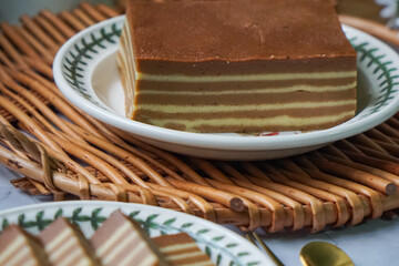 A traditional Indonesian steamed layer cake with alternating vibrant layers, showcasing a soft,...