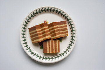 A traditional Indonesian steamed layer cake with alternating vibrant layers, showcasing a soft, moist texture and rich flavors, perfect for festive occasions.