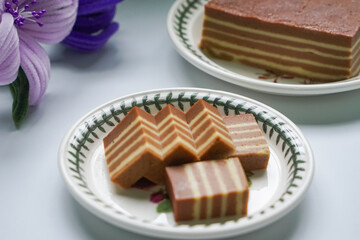 A traditional Indonesian steamed layer cake with alternating vibrant layers, showcasing a soft,...