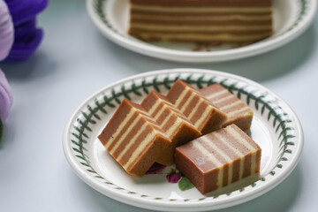 A traditional Indonesian steamed layer cake with alternating vibrant layers, showcasing a soft, moist texture and rich flavors, perfect for festive occasions.
