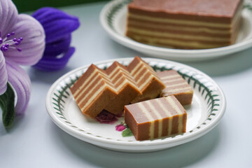 A traditional Indonesian steamed layer cake with alternating vibrant layers, showcasing a soft,...