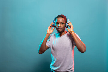 Portrait of african american man wearing wireless headphones and standing against an isolated...