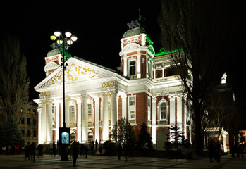 National Theatre Ivan Vazov building is brightly illuminated and stands out against evening sky....