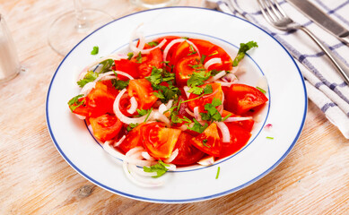 Vegetarian salad with tomatoes, onion, greens and olive oil at plate