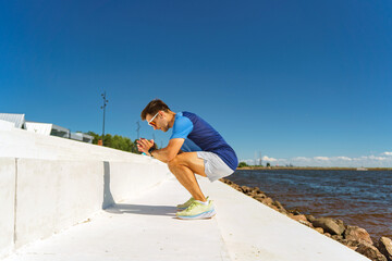 Focused Athlete Performs a Squat Exercise by the River Under a Clear Blue Sky During a Sunny...