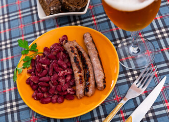 Fried red beans and sausage served on plate and decorated with greenery, traditional dish of Catalonia. Butifarra con alubias