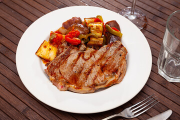 Appetizing beef entrecote with baked vegetables served at plate