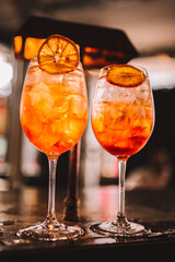 Two Aperol Spritz cocktails with orange garnish, close up shot with selective focus.