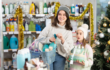 Woman in a winter hat and sweater with a full basket of goods and household chemicals, she stands...