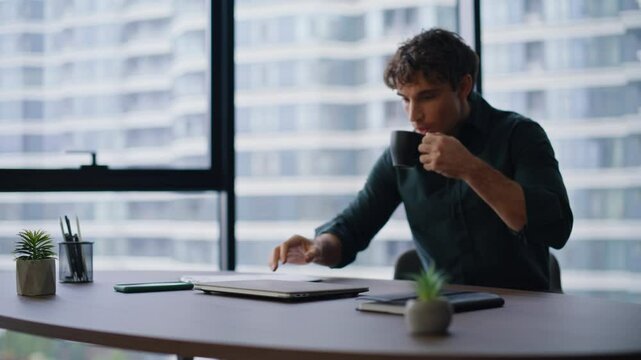 Young businessman start workday sit down office desk with coffee cup closeup. 