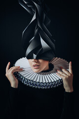 Portrait of Elegant Woman Wearing a Ruffled Collar and Ornamental Paper Hat in a Dark Theatrical...