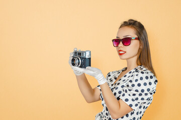 Smiling Brunette Woman Holding a Vintage Camera Against Peach Background, Capturing Memories, Exploring Photography, and Cherishing Nostalgia