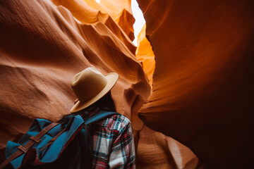 Backpacker Standing Inside a Narrow Canyon with Sunlit Orange Sandstone Walls and a Serene Sky View, Antelope Canyon © Victoria Nefedova