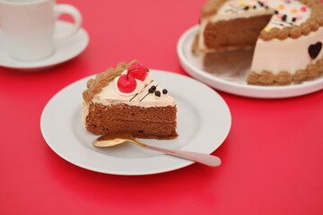a slice of chocolate cake served on a white plate with a golden spoon resting beside it