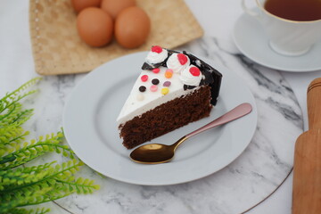 a single slice of chocolate cake served on a white plate. The cake has a rich, moist chocolate base topped with a layer of white frosting