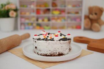 The cake is coated with a layer of whipped cream, lightly covering the chocolate sponge beneath