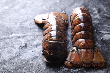 Raw lobster tails on dark table, closeup. Space for text
