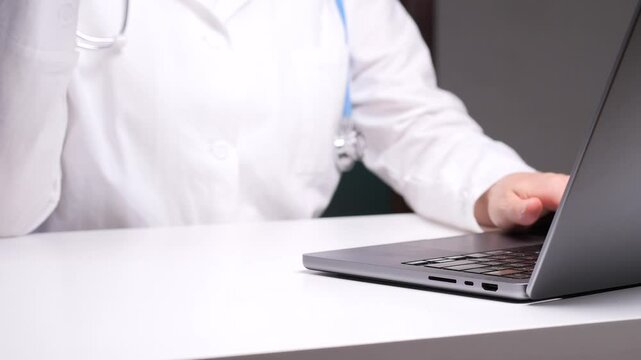 Doctor working on laptop and drinking coffee at desk