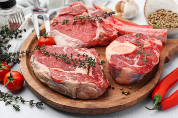 Pieces of raw beef, spices and products on light grey table, closeup