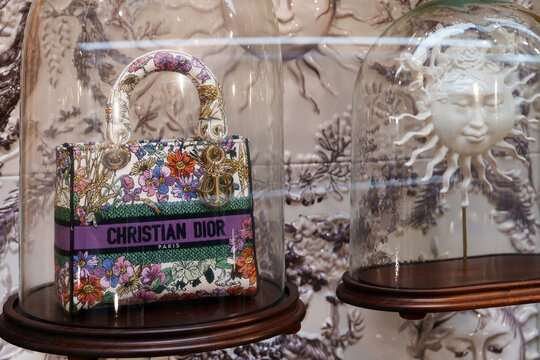Milan, Italy - 24.04.2024: Luxurious designer Dior handbag display in floral dome setting with intricate sun motif.