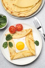 Delicious crepes with egg, tomato and basil on light grey table, flat lay