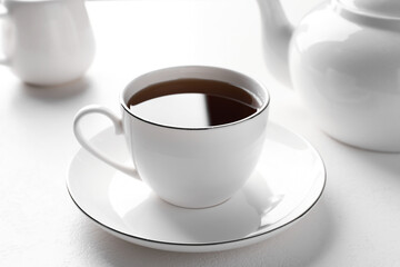 Freshly brewed tea in cup on white table, closeup