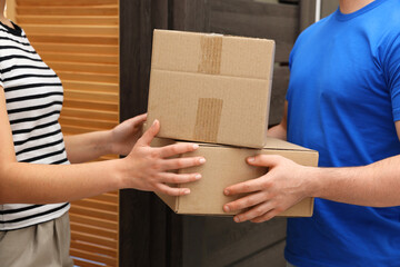 Courier giving parcels to receiver indoors, closeup