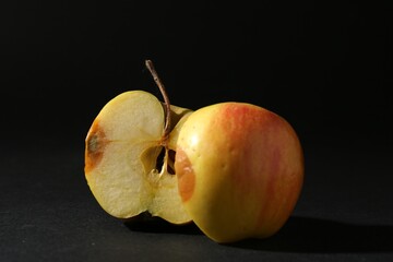 Halves of rotten apple on black background, closeup