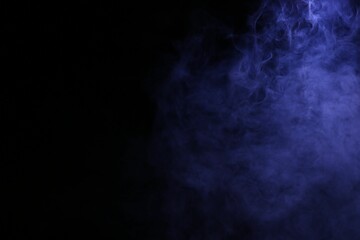 Beautiful smoke in blue light on dark background. Space for text