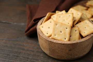 Tasty salty crackers on wooden table, closeup. Space for text