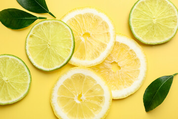 Slices of lemons and limes on yellow background, flat lay