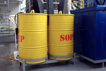 Two yellow drums of SOPEP spill kit as a part of the ship oil pollution emergency plan situated on deck of merchant ship.