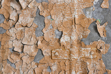 Peeling paint on the wall. Old concrete wall with cracked flaking paint. Weathered rough painted surface with patterns of cracks and peeling. Grunge texture for background and design. High resolution.
