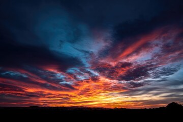 Fototapeta premium Vibrant clouds in various colors fill the sky as the sun sets on the horizon.