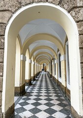 Checkered floor vanishing under a series of arches in a cloister