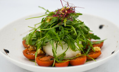Ensalada con mozzarella, tomates y rúcula en un plato blanco