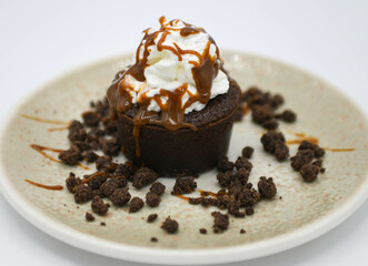 Muffin de chocolate con crema batida y chispas de chocolate sobre fondo blanco