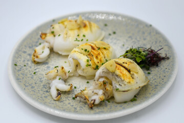 Calamares a la plancha en un plato aislado sobre fondo blanco. Enfoque selectivo.
