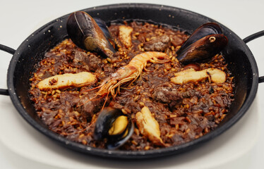 Paella de marisco en una sartén sobre un fondo blanco
