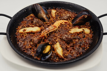 Paella de marisco en una sartén sobre un fondo blanco