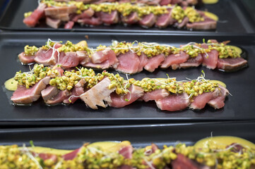 carpaccio di pesce crudo servito sul bancone di una pescheria in un piatto di plastica