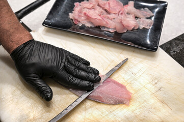 carpaccio di pesce crudo servito sul bancone di una pescheria in un piatto di plastica