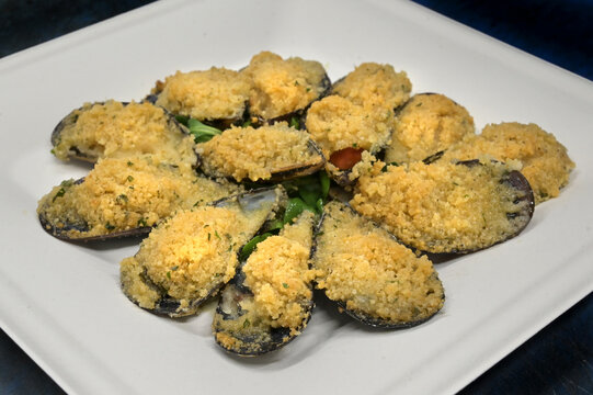 cozze ripiene gratinate servite su di un piatto di carta