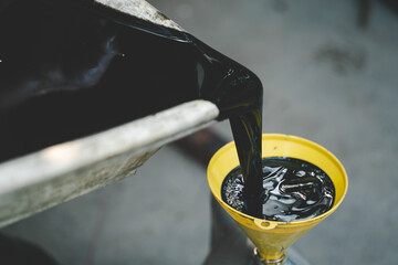 Old engine oil. Pouring old black oil of car engine from oil pan into bottle on top view...