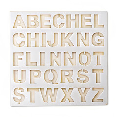 "Stencil sheet with alphabet cutouts on white"