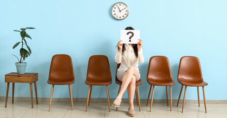 Female applicant holding paper with question mark in room