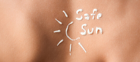 Text SAFE SUN made of sunscreen cream on woman's back, closeup