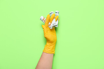 Fototapeta premium Woman in medical glove with money on green background