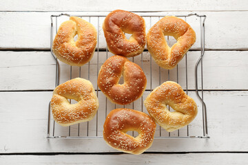 Grid of tasty bagels with sesame seeds on light wooden background